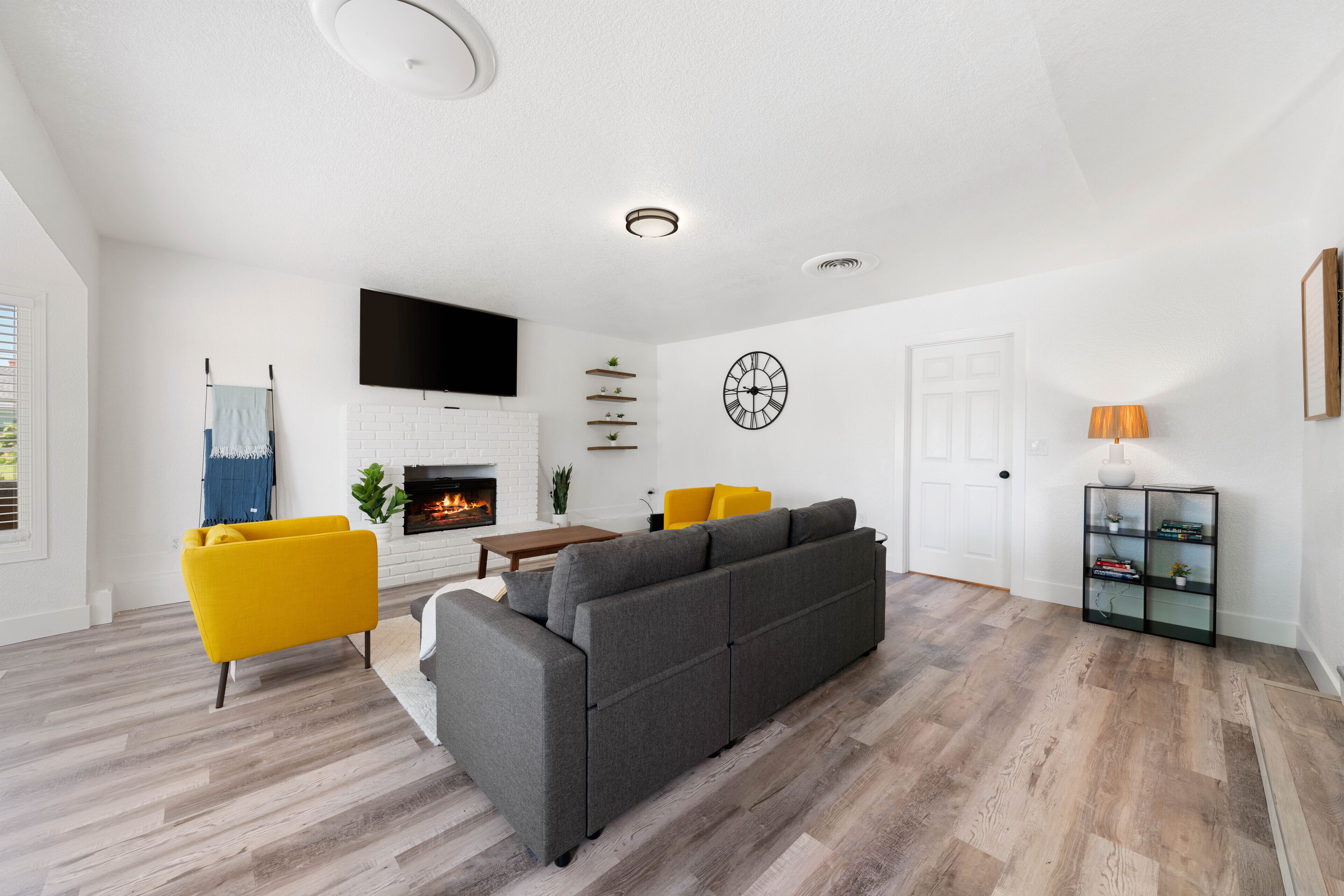 Un salon moderne avec un canapé gris, un fauteuil jaune et une cheminée.
