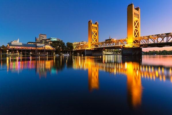 A bridge with two towers, a waterfront, and buildings in the background.