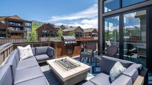 Ein moderner Außenbereich mit integriertem Feuerkorb, Sitzgelegenheiten und einer verglasten Terrasse.
