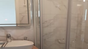 A modern bathroom with a glass-enclosed shower, a white sink with a wooden countertop, and a mirror above the sink. - Apartments and Rooms Jokovic-standard Studio Apartment With Terrace and Partial Sea View (Zupa dubrovacka)