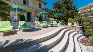 A pool area with lounge chairs and umbrellas, a stone staircase, and a building with balconies. - Apartments and Rooms Jokovic-standard Studio Apartment With Terrace and Partial Sea View (Zupa dubrovacka)