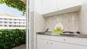 A modern kitchen with white cabinets, a stainless steel countertop, and a window overlooking a building. - Apartments and Rooms Jokovic-standard Studio Apartment With Terrace and Partial Sea View (Zupa dubrovacka)
