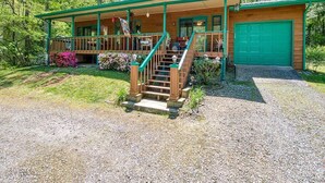 A cabin with a covered porch, a front staircase, and a green garage door. - Fast Wifi, covered porch, and fenced-in yard. Quiet neighborhood. Pet friendly! (Maggie Valley)