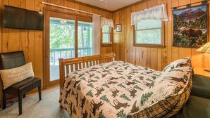 A bedroom with a bed, a chair, a television, and a ceiling fan. - Fast Wifi, covered porch, and fenced-in yard. Quiet neighborhood. Pet friendly! (Maggie Valley)