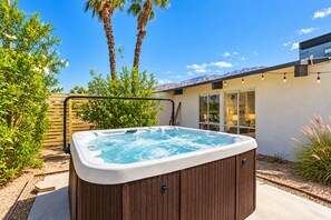 A hot tub in a backyard with a wooden deck, surrounded by greenery and a modern house. - 25% Off Oct 29-31 Perfect 4 Families Pool, Jacuzzi (Palm Springs)