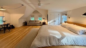 A bedroom with a large bed, a desk, and a chair. There is a ceiling fan and a window with blinds. - Luxury Redo: Hot Tub, Playroom, Fire-pit, Sleeps 12 (Egremont)
