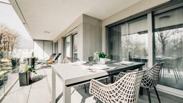 Un espace de restauration moderne, doté d’une grande table, de chaises blanches et offrant une vue dégagée grâce à de larges fenêtres.