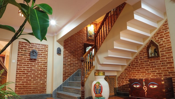 A staircase with a brick wall and wooden railing, leading to a second floor. - KAJI CHEN (Sunakothi)