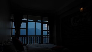 A dimly lit room with a large window overlooking a mountainous landscape. - KAJI CHEN (Sunakothi)