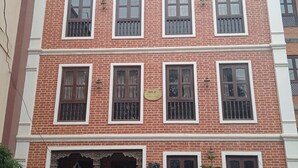 A multi-story brick building with multiple windows, some with decorative grills. - KAJI CHEN (Sunakothi)