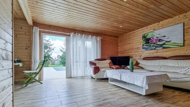 L'intérieur d'un chalet en bois, avec un canapé, une table et une chaise.