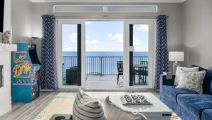 A living room with a sofa, a coffee table, and a view of the ocean through large sliding glass doors. - High-Rise Ocean View Condo at Laketown Wharf 2012 (Panama City Beach)