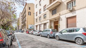 Une rue bordée de voitures garées et d’immeubles à plusieurs étages dotés de balcons.