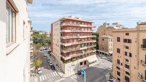 Un immeuble à plusieurs étages doté de balcons, d’un parking et surplombant un ciel dégagé.