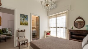 Une chambre à coucher avec un lit, une chaise, un radiateur, un tableau, un miroir et une fenêtre.