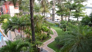 A lush garden with palm trees, a winding path, and a view of a body of water. - Kalim Résidence unit- 133 (Patong)