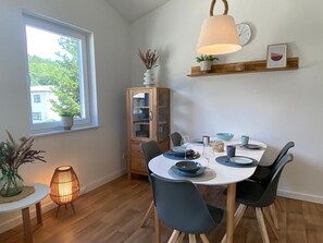 A dining area with a round table, chairs, and a hanging light fixture. - Haus Möwe - Ferienwohnung 5 "heringsmöwe" - Lietzow Appartementhaus Möwe (Lietzow)