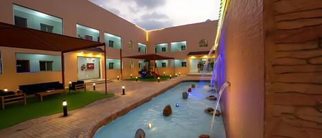 A courtyard with a water feature, seating areas, and a play structure.