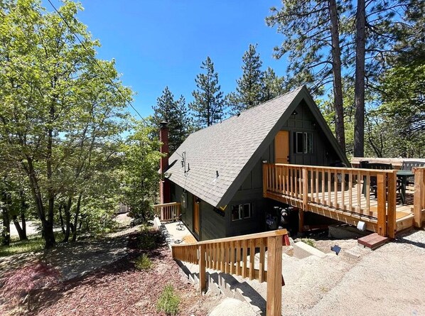 A cabin with a wooden deck, a small porch, and a stone pathway leading to the entrance.