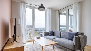 A modern living room with a grey sofa, a wooden coffee table, and a TV on a stand.