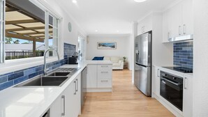 A modern kitchen with white cabinetry, a stainless steel refrigerator, and a built-in oven. - Beach House With Pool, Pets Welcome! (Coolum Beach)