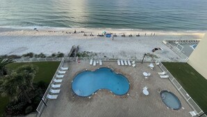 A beach view with a pool area, including a large pool, smaller pool, and lounge chairs. - Uncrowded Corner Beachfront 3BR w/3 New Spa Baths (Gulf Shores)