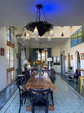 Enjoy meals in this elegant dining area with a long table, black chairs, and a unique chandelier.
