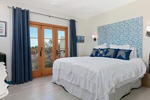 Relax in this serene bedroom with a large bed, sliding glass door to an outdoor area, and stylish headboard.