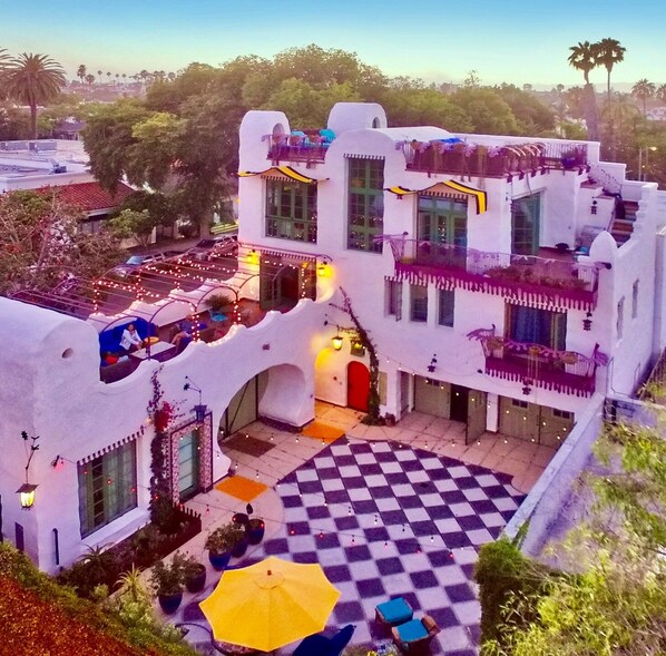 Stunning multi-story building with a unique architectural style, featuring a courtyard with a checkered floor and outdoor seating areas.
