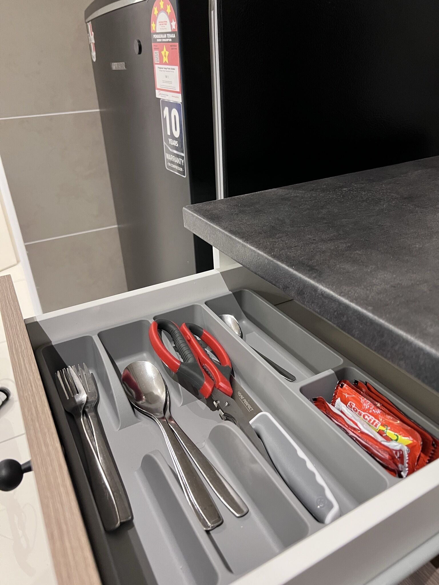 Eine Schublade mit Besteck, einer Schere und einer Tüte Snacks.