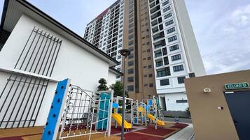 A playground with slides and climbing structures, adjacent to a building with a sign reading "KELUAR".