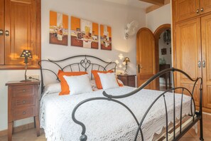 Un dormitorio con una cama, armarios de madera, un aparador y obras de arte en la pared.