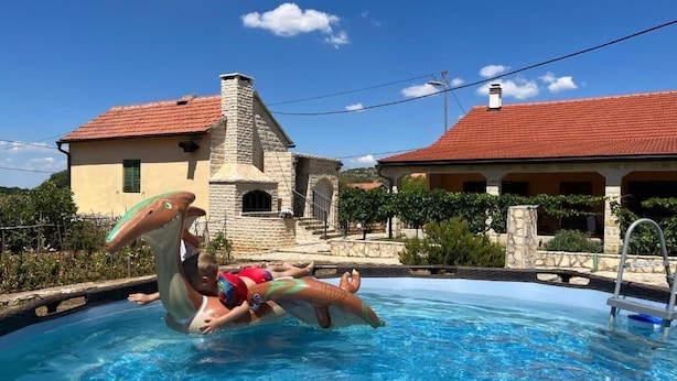 A swimming pool with two people in a dolphin float. - Runaway Cottage Villa (Unesic)