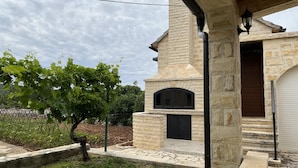 A stone building with a black door and a small arched window. - Runaway Cottage Villa (Unesic)