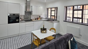 Una cocina compacta con armarios blancos, horno empotrado y ventana con vistas a edificios.