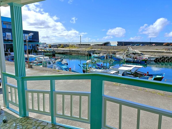 A marina with boats docked, a clear sky, and a building with blue and white exterior in the background.