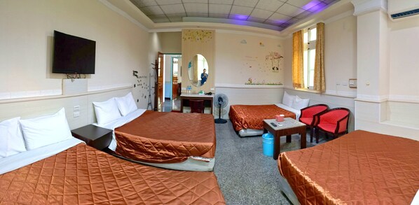 Habitación de hotel con dos camas, un escritorio, una silla, un televisor y una ventana con cortinas.