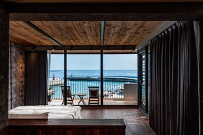 Ein Schlafzimmer mit einem großen Fenster mit Blick auf Strand und Meer.