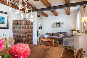 A cozy living room with a wooden table, a sofa, a bookshelf, and a decorative hanging light fixture.