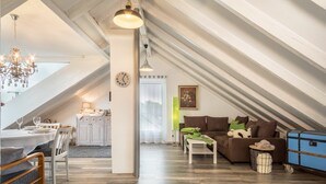Ein geräumiges Loft mit Essbereich, einer Couch, einem kleinen Tisch und einem blauen Truhenkasten.