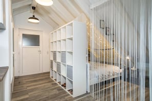 Een slaapkamer met een bed, een witte inbouwkast, een witte deur en een houten vloer.