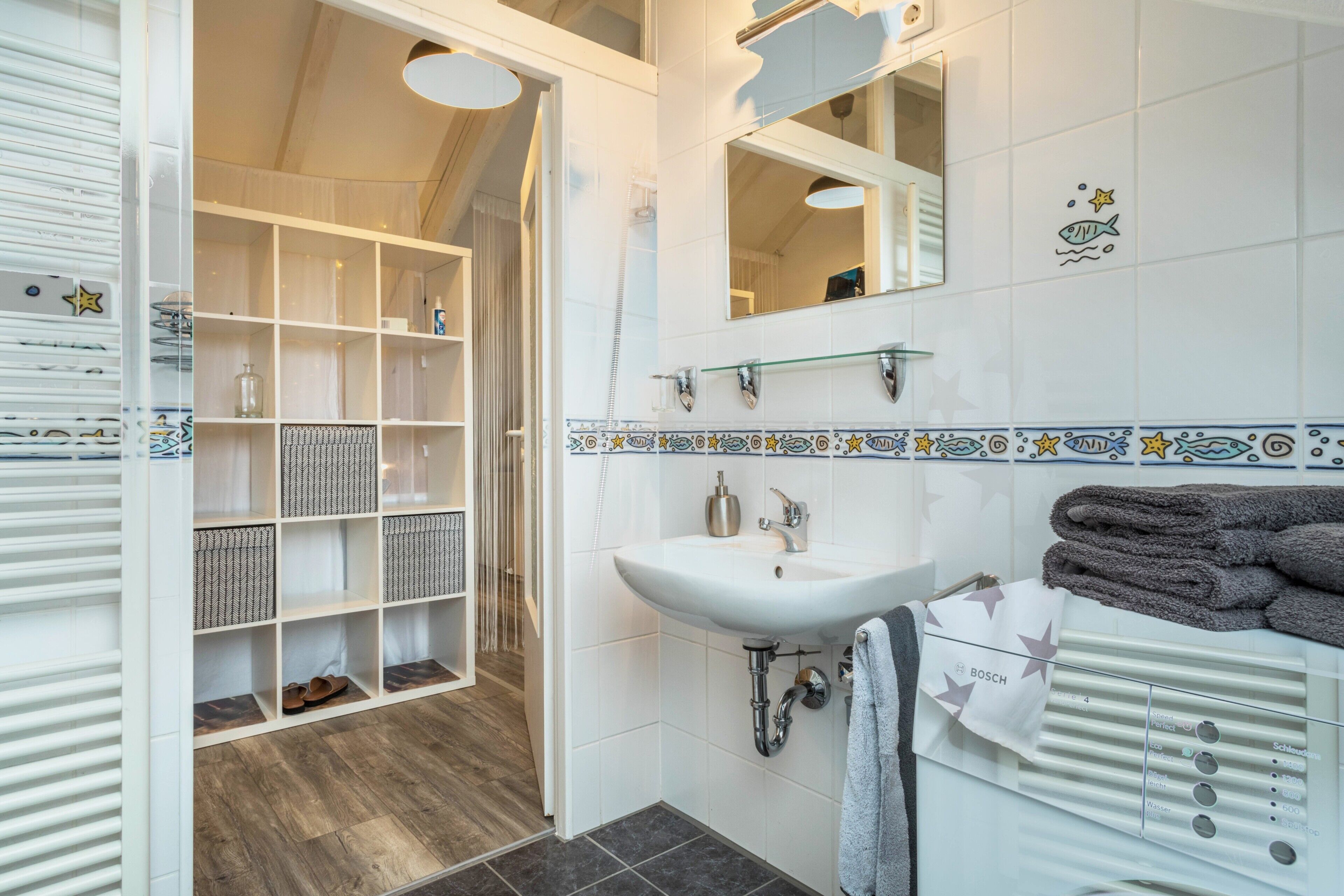 Une salle de bain moderne avec un lavabo blanc, un miroir et un porte-serviettes.