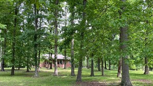 Une zone boisée avec un bâtiment en briques entouré de grands arbres.