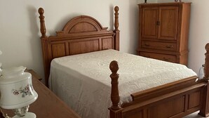 Une chambre à coucher avec un lit en bois, une table de chevet avec une lampe et une commode en bois.