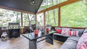 Relax in a serene outdoor space with a comfortable sofa, a glass-top table, and a black grill.