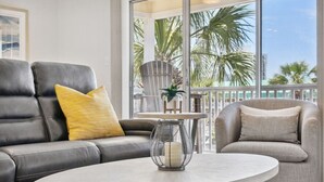 A modern living room with a leather sofa, a grey armchair, and a round coffee table. - Renovated Condo: 3 Min Beach Walk (Destin)