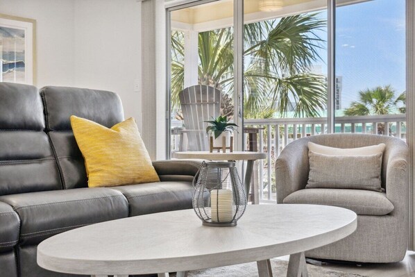 A modern living room with a leather sofa, a grey armchair, and a round coffee table.