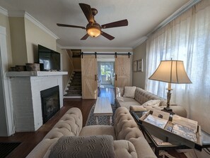 Relax in this inviting living room with a fireplace, comfortable seating area, and mounted TV.