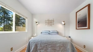 A bedroom with a bed, two bedside lamps, a window, and a framed picture on the wall. - Comfortable Modern Condo near Downtown (Friday Harbor)