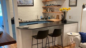 A modern kitchen with a central island, bar stools, and a small round table. - Comfortable Modern Condo near Downtown (Friday Harbor)